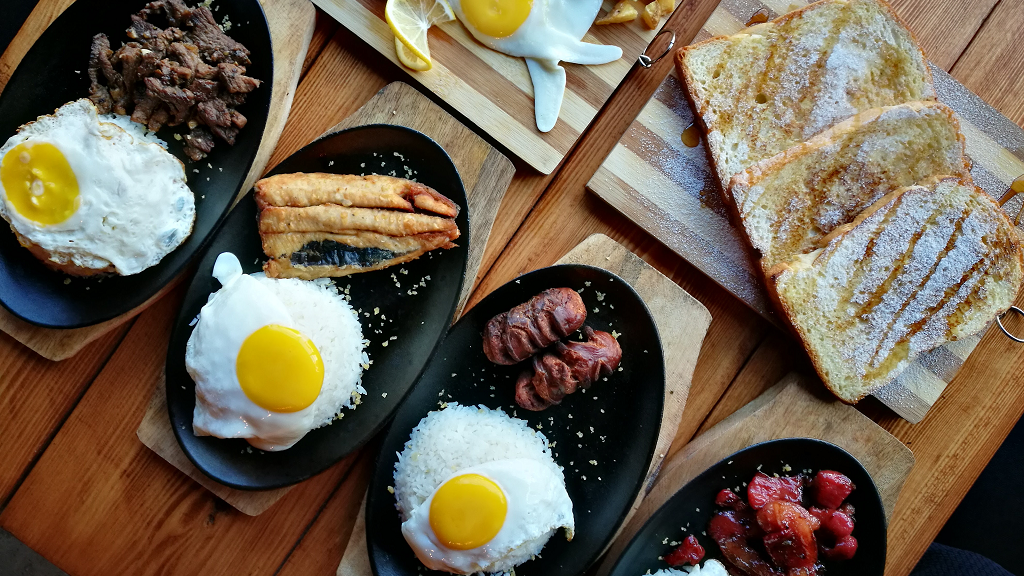 Τηγάνια με τηγανητά αυγά και ποικιλία κρεάτων για πρωινό, σερβιρισμένα σε ένα τραπέζι το ένα δίπλα στο άλλο